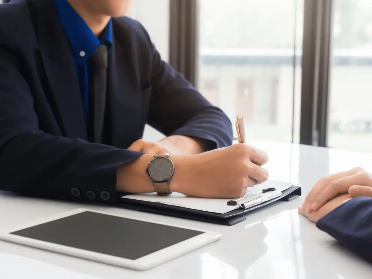 Business professional in a suit taking notes on a clipboard during a meeting, symbolizing legal and compliance discussions under Quebec language laws.