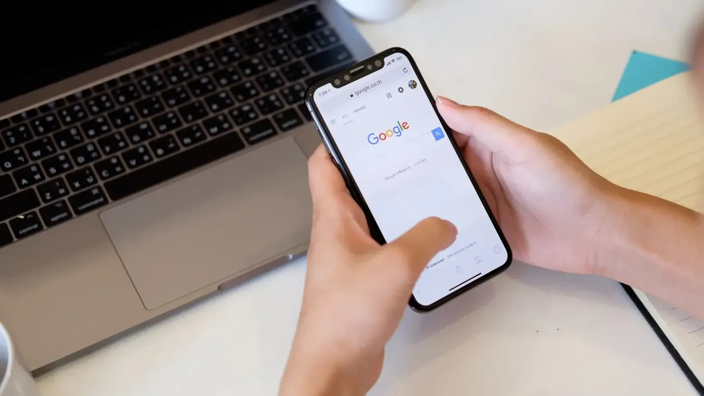 Person using a phone and a laptop to compare translations and check Google Translate accuracy.