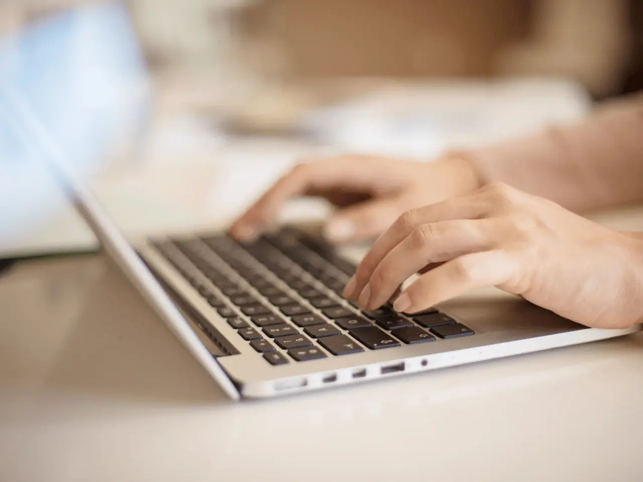 Close-up of hands typing on a laptop keyboard, representing online translation work and machine translation processes.