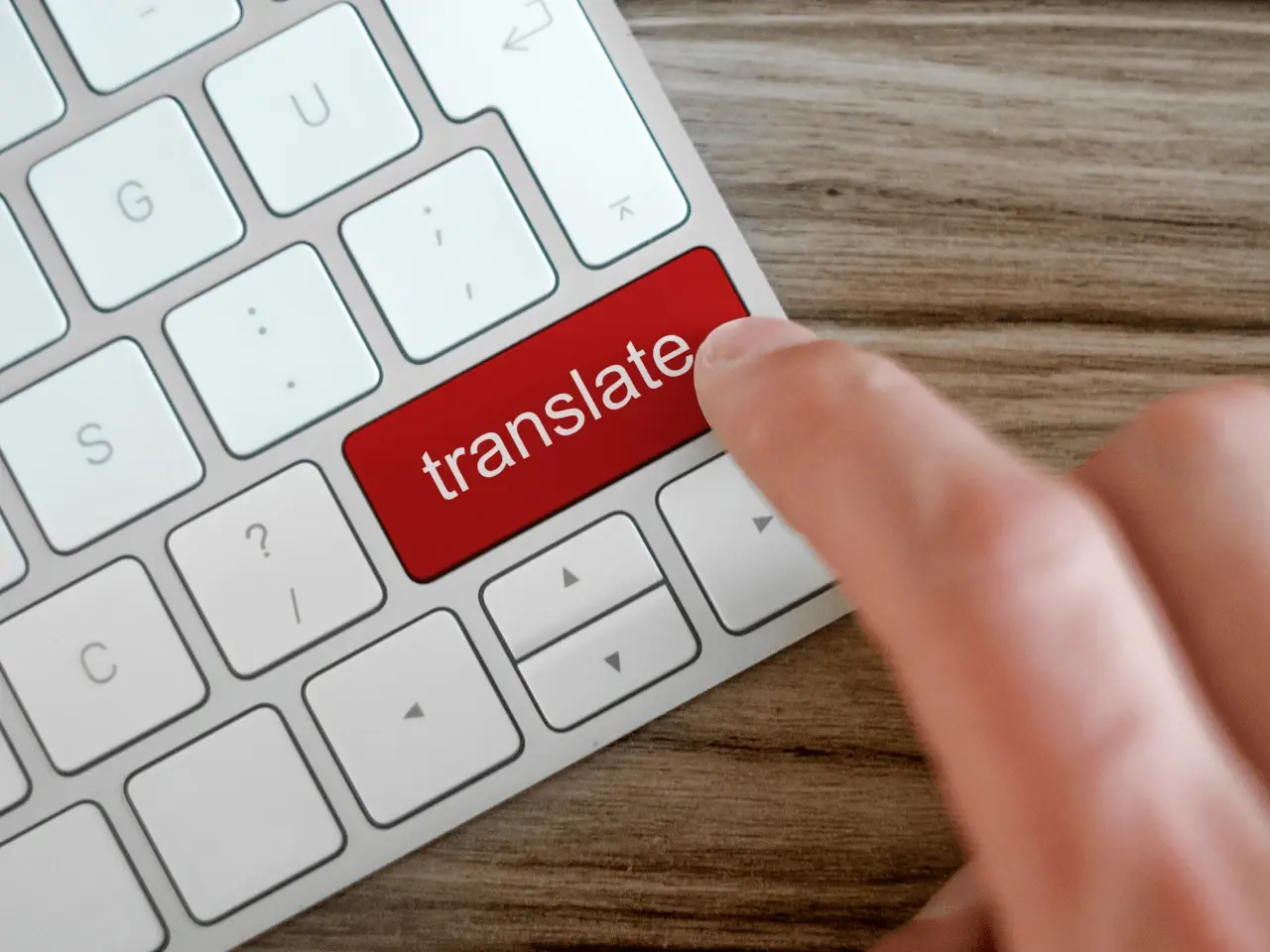 Finger pressing the red translate key on the computer keyboard, symbolizing instant machine translation.