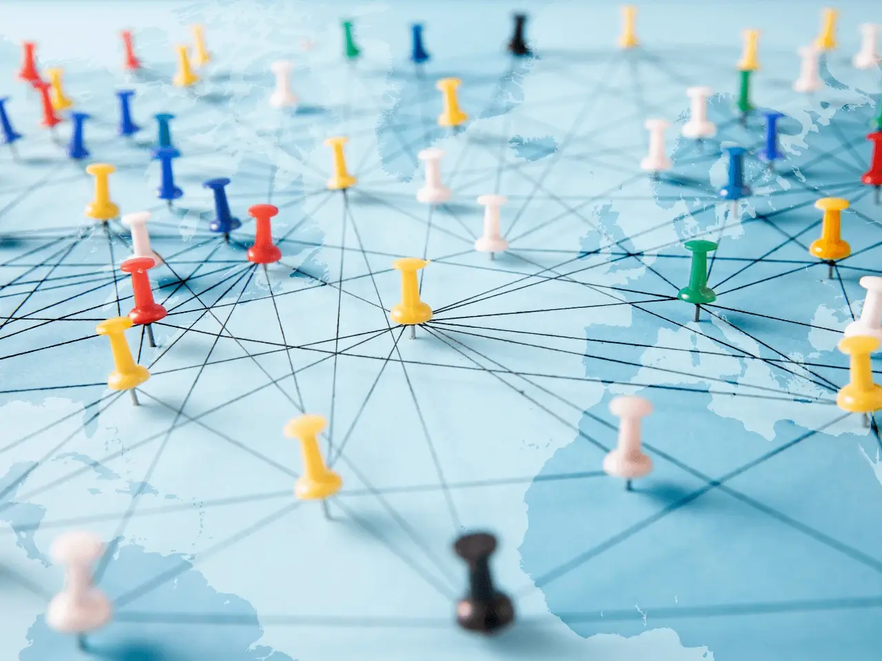 Push pins connected by lines across a world map, symbolizing international marketing networks and global reach.