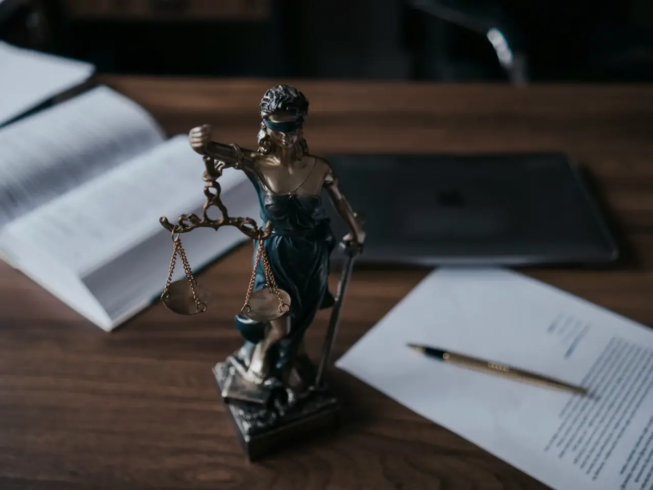 Lady Justice statue with scales on a desk beside legal documents, symbolizing the context and purpose of Quebec’s Bill 96 and its legal framework.