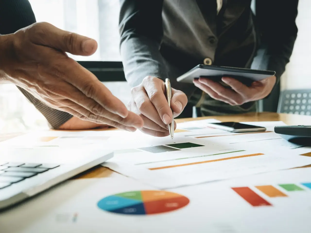 Business professionals reviewing charts and documents on a desk, illustrating the economic and operational challenges Quebec businesses face under Bill 96 language compliance rules.