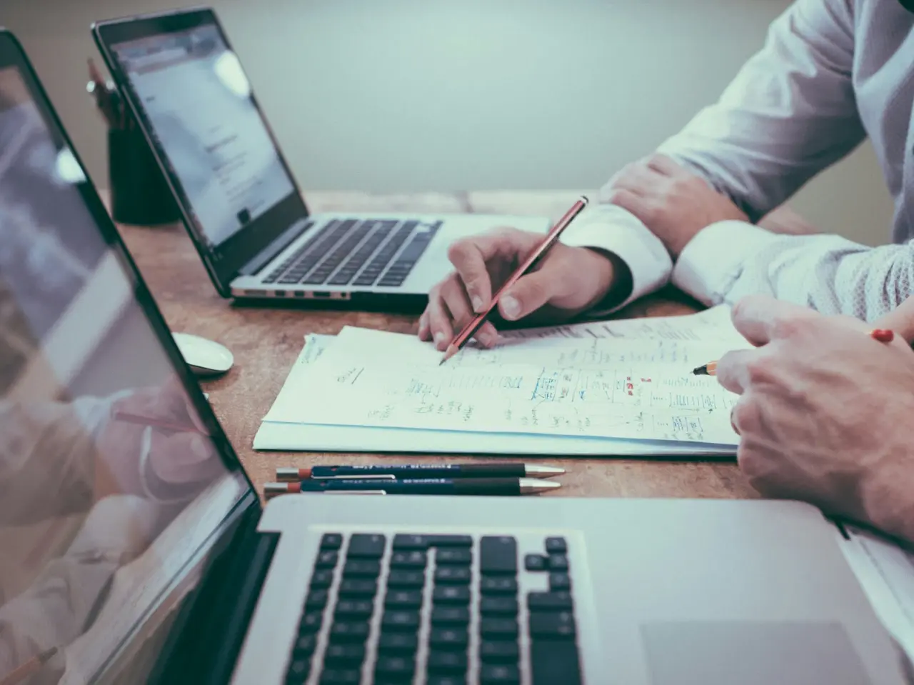 Two professionals working on compliance documentation with laptops and notes, symbolizing support services for small and medium-sized businesses adapting to Quebec’s Bill 96 requirements.