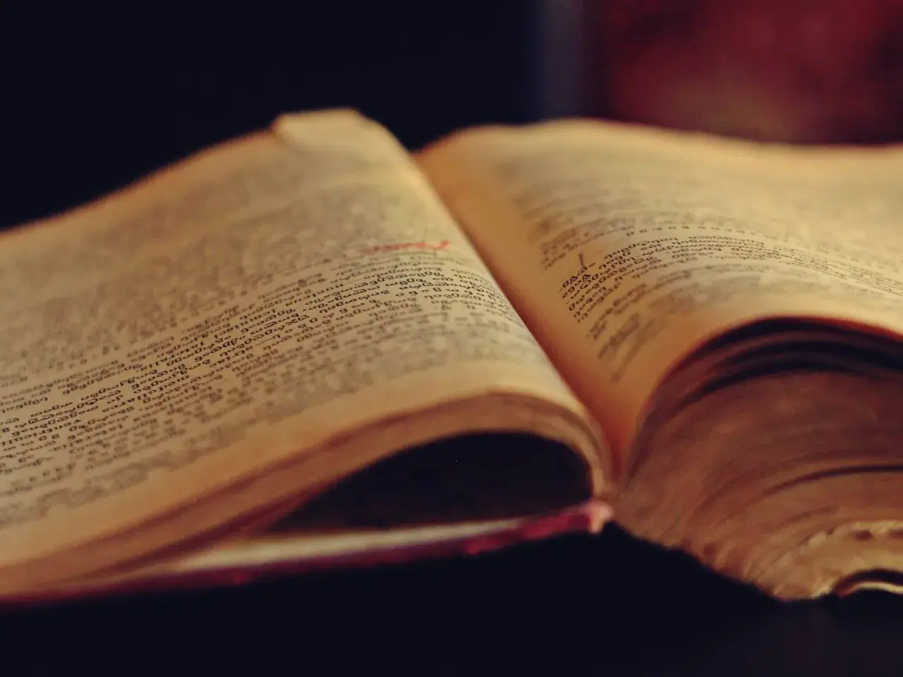An open old book with French text, representing the historical evolution of vocabulary and grammar in Quebec French and European French.