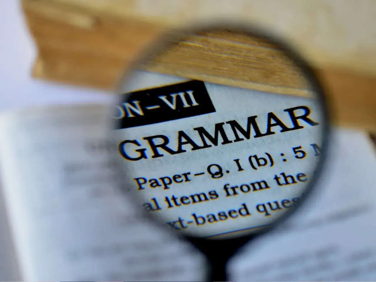 The word “grammar” magnified through a lens in a dictionary, symbolizing differences in language structure between Quebec French and European French.