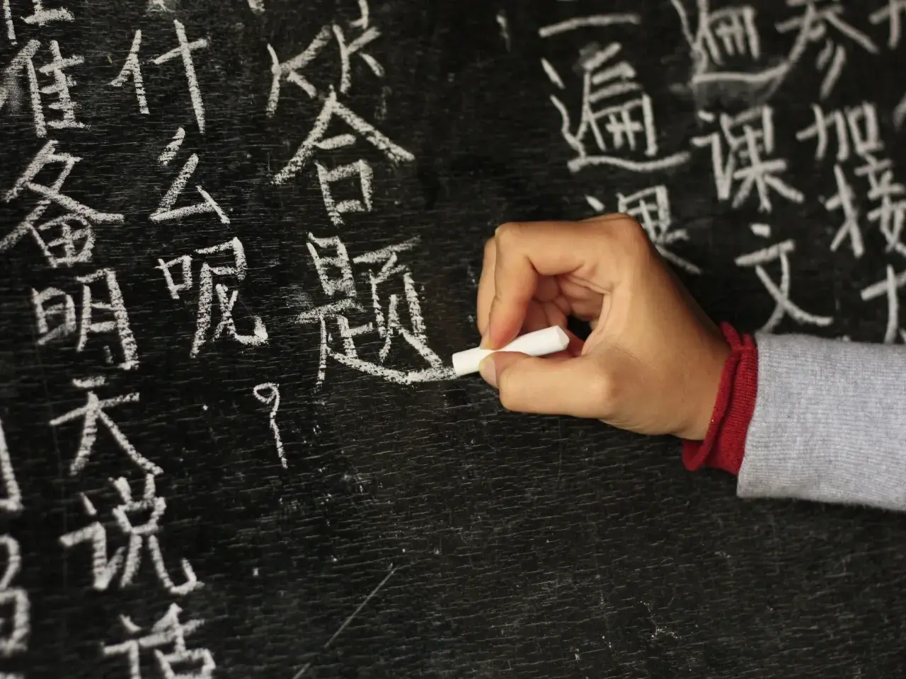 Handwriting Chinese characters on a chalkboard, showing Chinese writing practice.