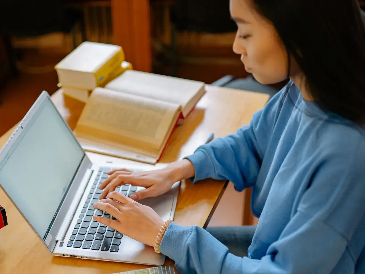 Person working on a laptop with Chinese study materials, representing Chinese localization for business.
