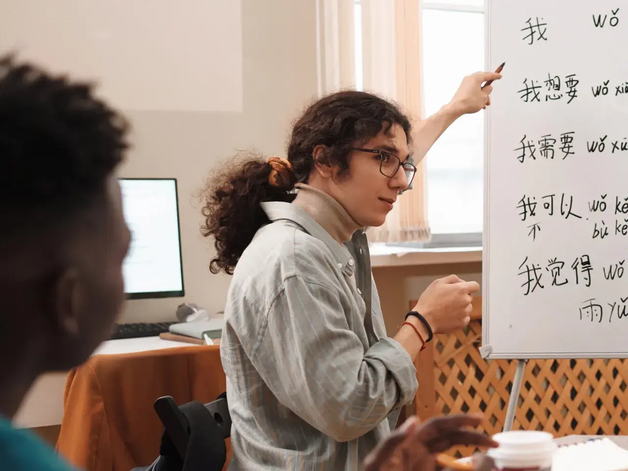 Teacher explaining Chinese characters on a whiteboard, representing language differences by region.