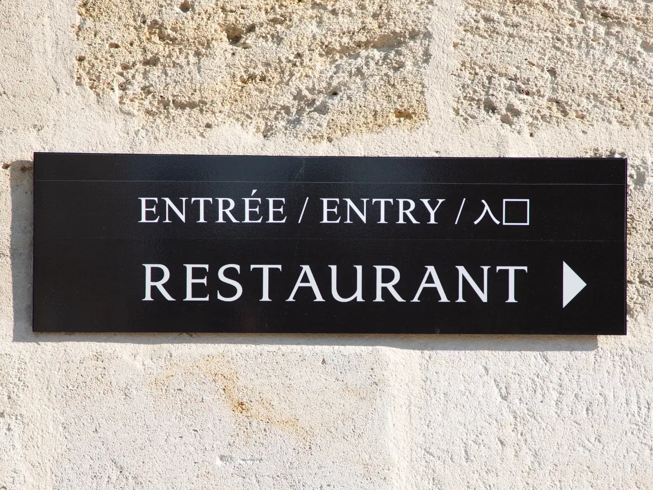 Arrow sign for restaurant entry in multiple languages.