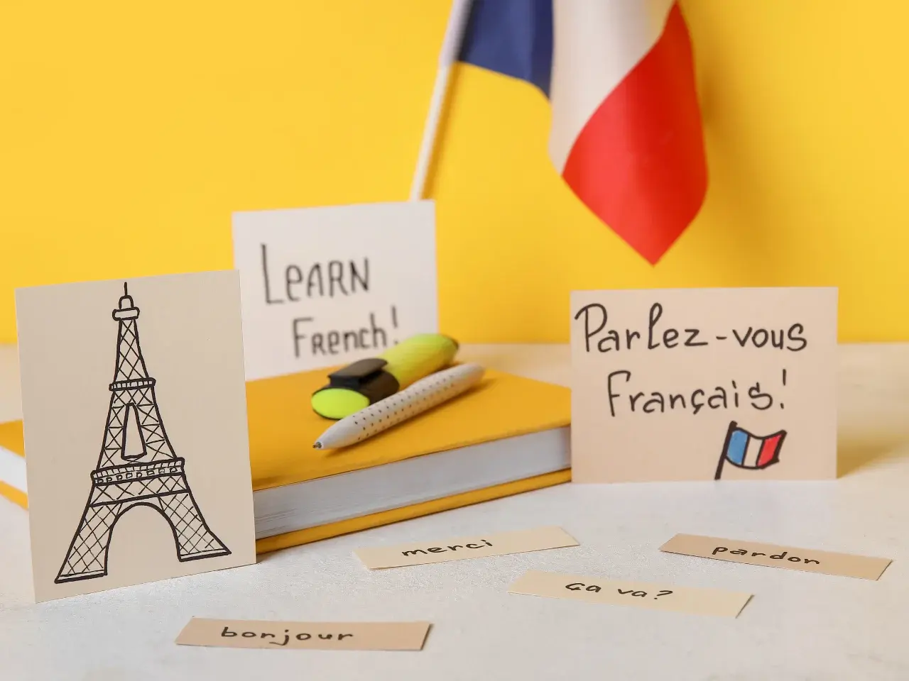 “Learn French” paper with an Eiffel Tower drawing, a French flag, and stationery symbolizing bilingual culture.