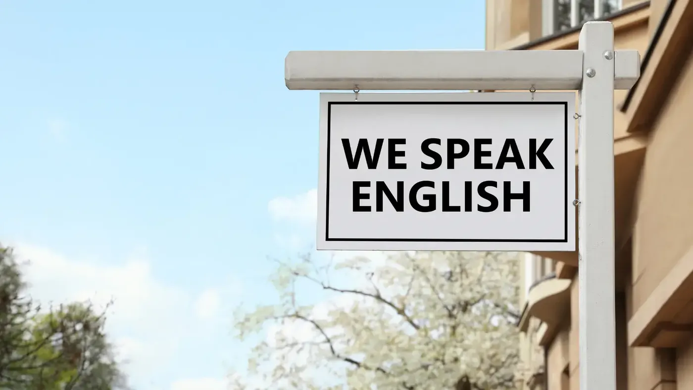 Sign reading “We Speak English” representing global use of the English language.