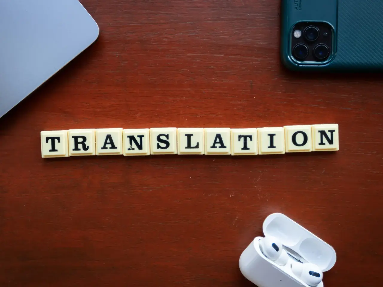 Word “Translation” spelled with letter tiles on a wooden desk beside a smartphone and laptop, representing visibility across Canada’s top search engines.