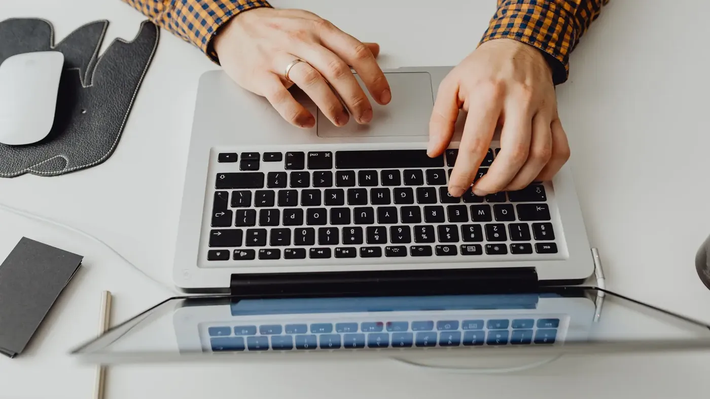 Hands typing on a laptop while drafting creative marketing content for transcreation.